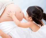 Loving girl stroking the pregnant belly of her mother with tenderness